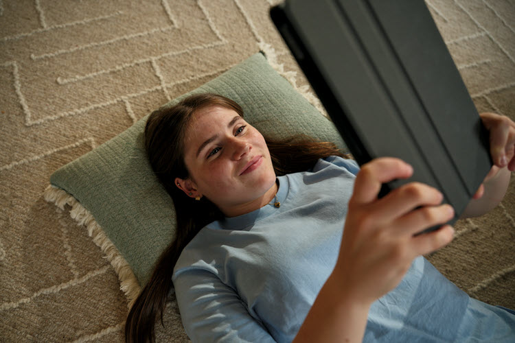 Girl on floor looking up at a tablet