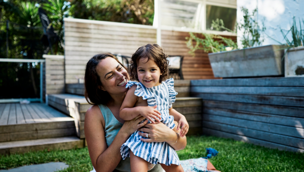 Mother holding daughter in garden smiling