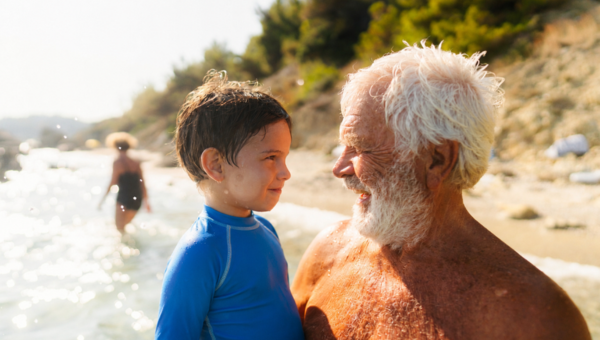 Grandpa holding grandson smiling at the beach