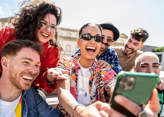 Friends taking a selfie outside in the sun.