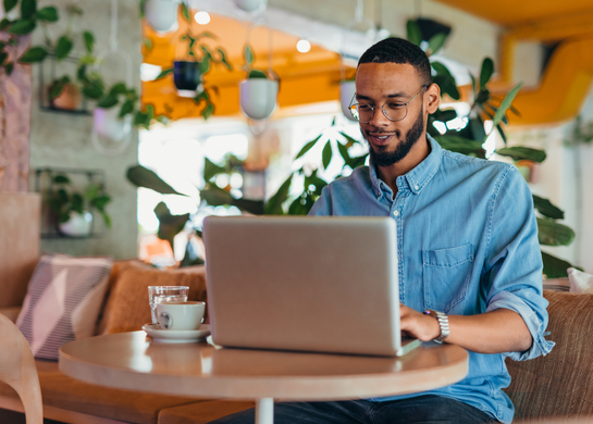 Man working on laptop at cafe.