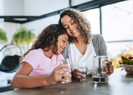 Woman and daughter embracing in kitchen.
