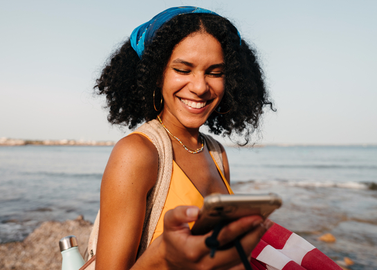 Woman at beach checking phone.