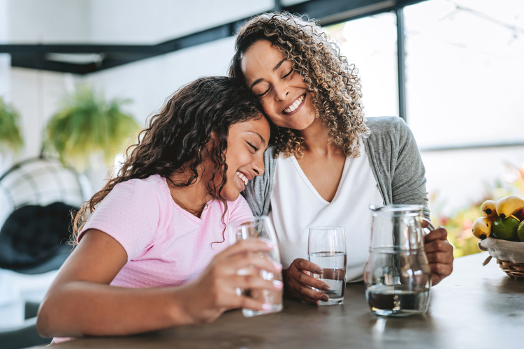 Woman and daughter embracing in kitchen.