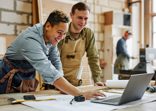 Two tradesmen at desk on jobsite. 