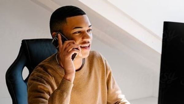 Man in home office on phone at desk.