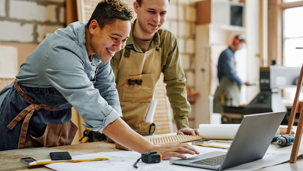 Two tradesmen at desk on jobsite. 