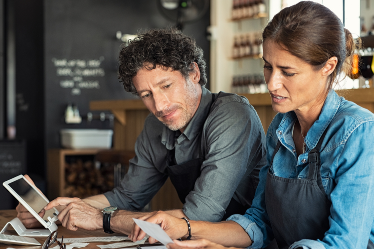 Man and woman recording receipts in cafe.