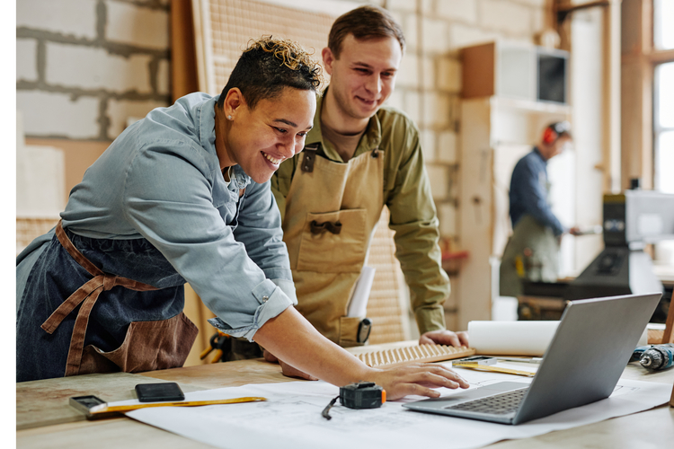 Two tradesmen at desk on jobsite. 