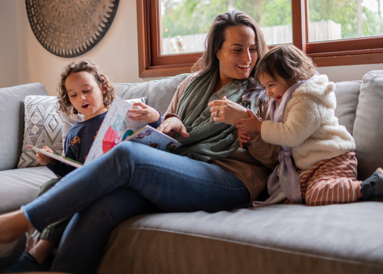 Woman on couch with two kids storytelling. 