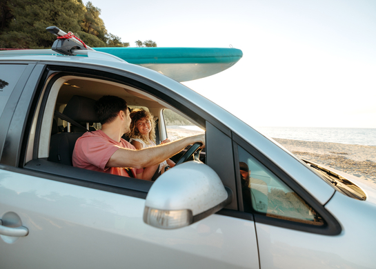 Young couple in car at beach. 