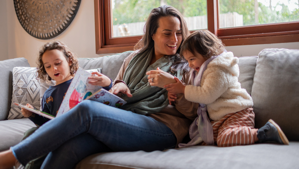 Woman on couch with two kids storytelling. 