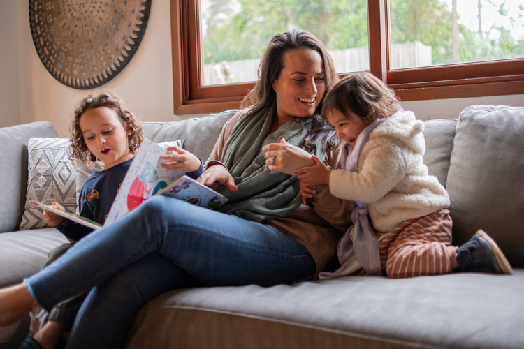 Woman on couch with two kids storytelling. 