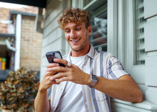 Young blond man checking his phone outside.