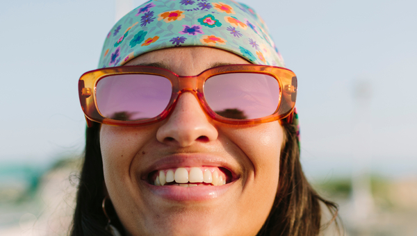 Woman outside in sunglasses, smiling.