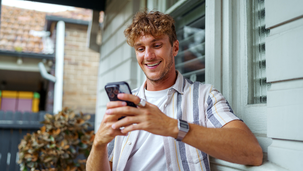 Young blond man checking his phone outside.