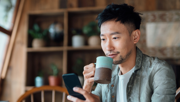 Man sipping tea while checking his phone. 