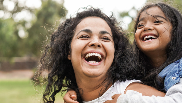 Young mother with daughter at park piggyback
