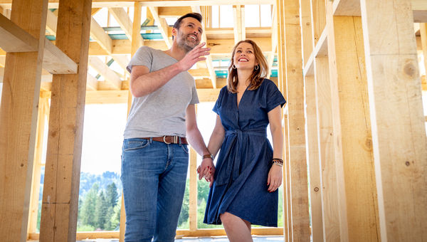 Couple inspecting new house frame. 