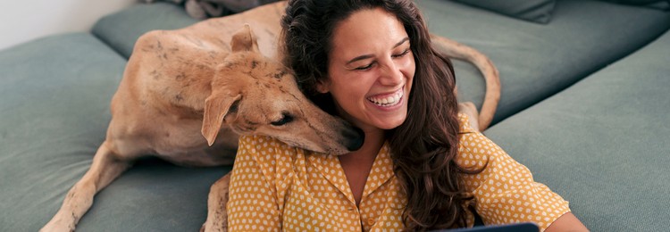 Woman and dog on the couch with a laptop.