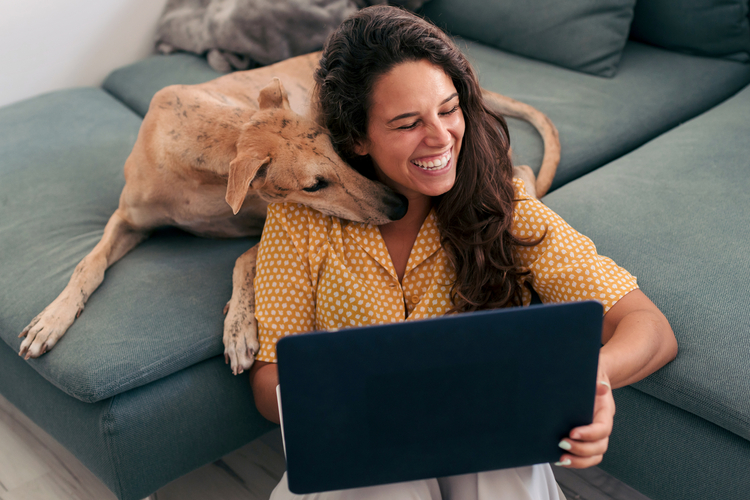 Woman and dog on couch with laptop.