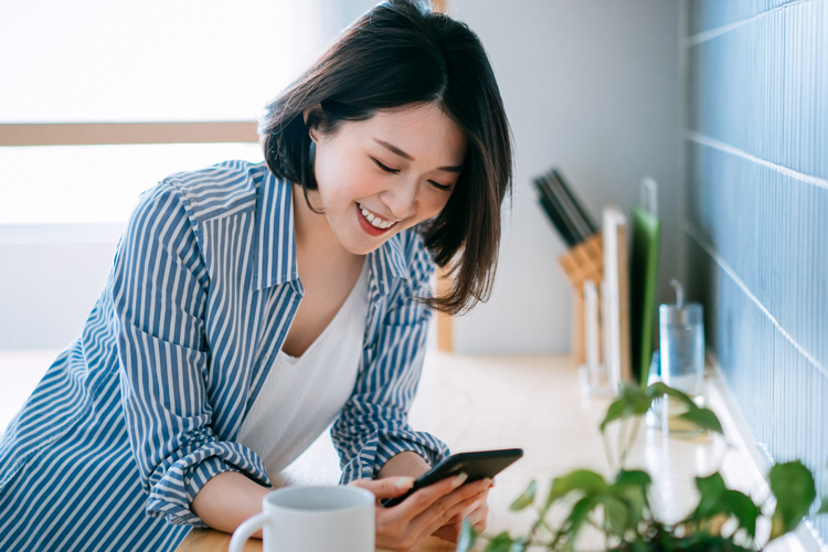 Woman checking phone while drinking coffee.