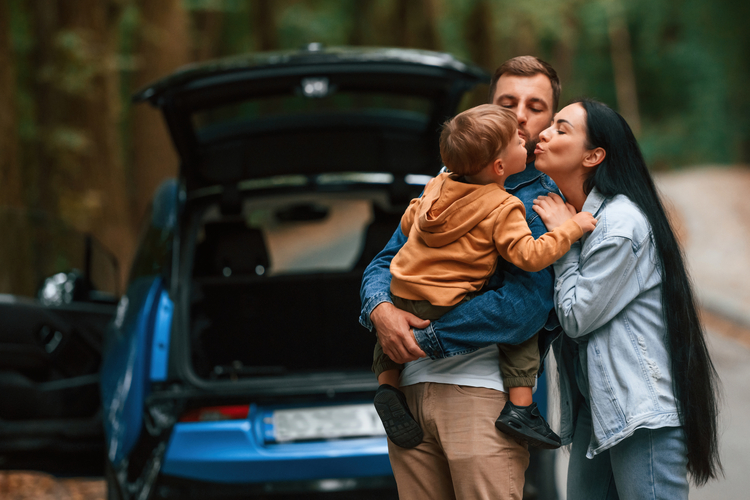Young family hugging on a forest road trip.