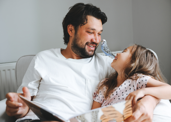 Father reads to daughter on the couch