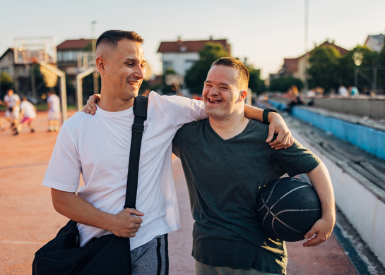 man with arm around young man with ball