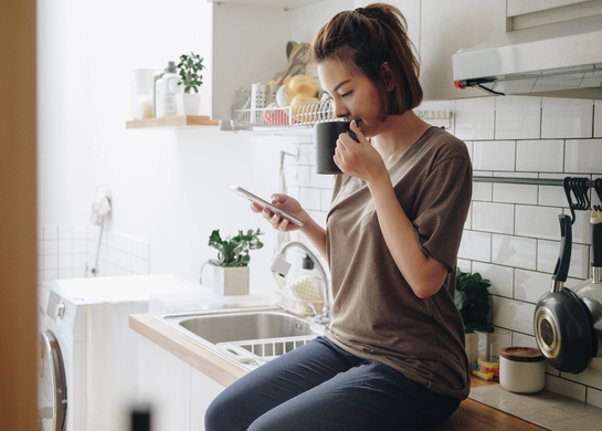 Woman sits at her kitchen bench.
