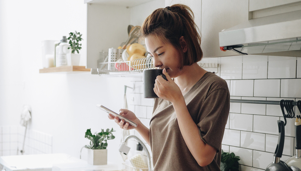 Woman sits at her kitchen bench.