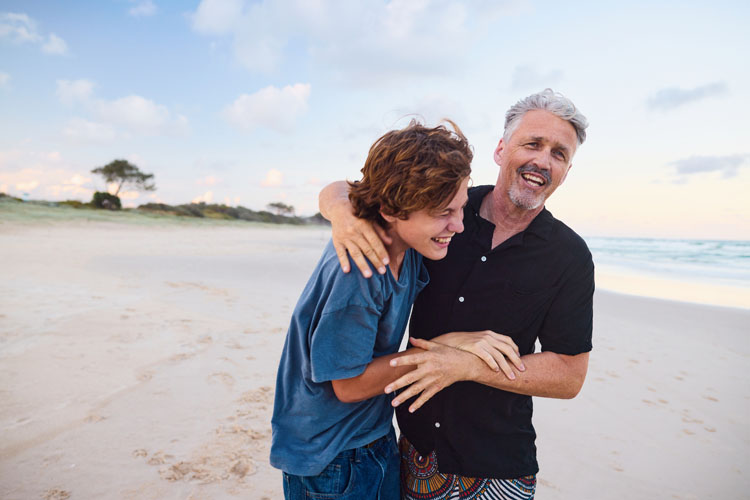 A father and son walk along the beach.