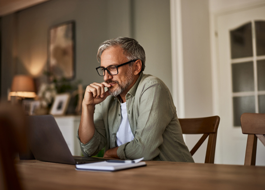 A man using a laptop at the dining room table.