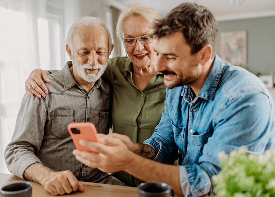 Adult son shows parent something on a mobile phone.