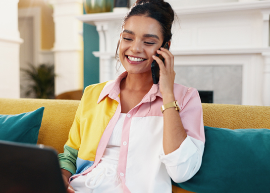 Woman talks on her phone sat on the couch.