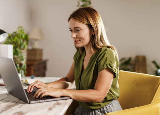 Woman sits at a marble table using her laptop.