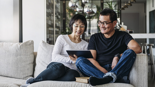 A couple sat with a tablet on the couch.
