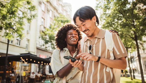 A couple use a mobile phone on the street.