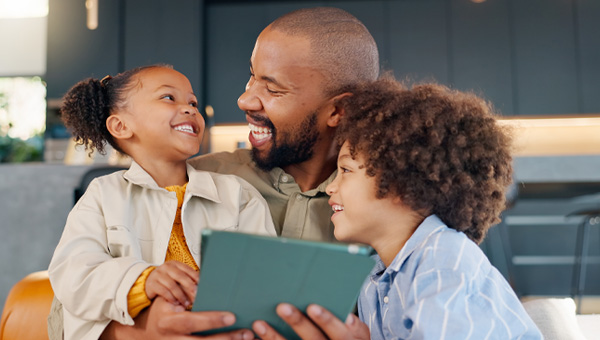 A father, daughter and son use a tablet.