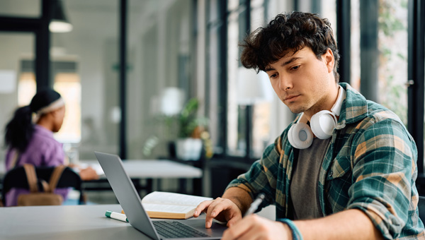 Man studies with a laptop while wearing headphones.