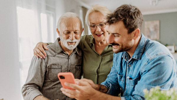 Adult son shows parent something on a mobile phone.