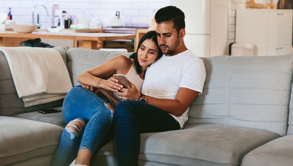 Young couple cuddles on their couch