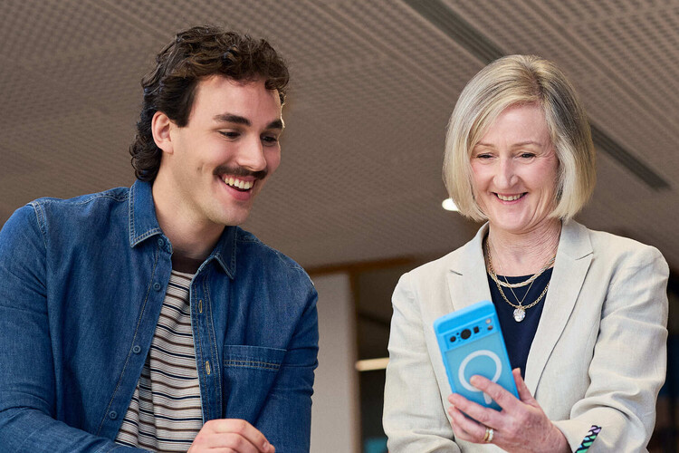 A customer and a People First Bank employee looking at a mobile phone together. 