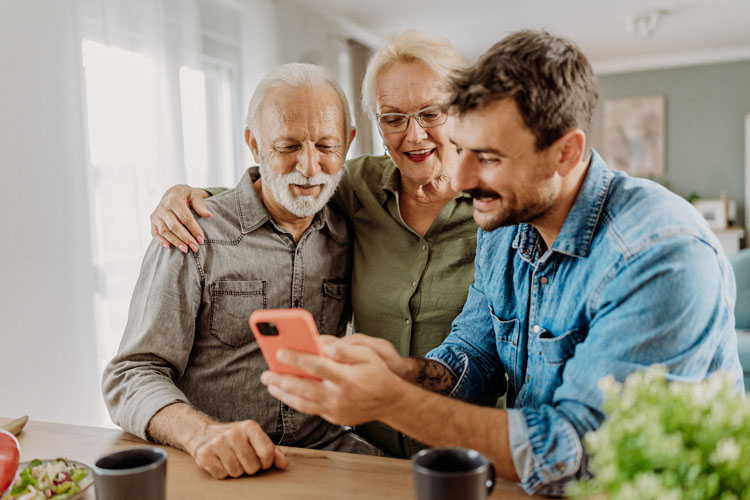 Adult son shows parent something on a mobile phone.