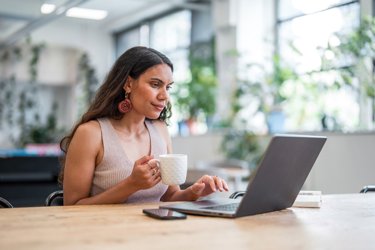 woman holding mug on laptop