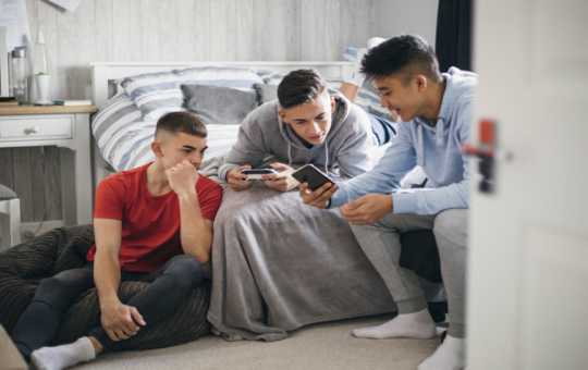 Adolescent boys game and look at mobile