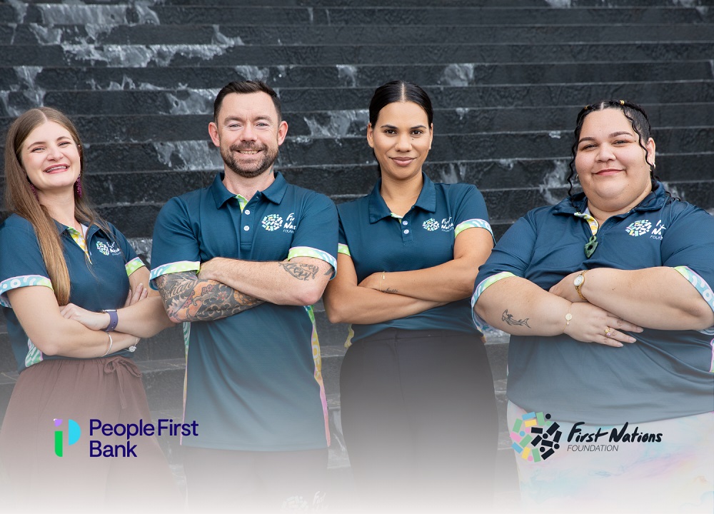Four team members in matching uniforms stand with arms crossed in front of a dark textured wall.