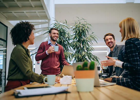 A team of young office workers laughing over coffee.
